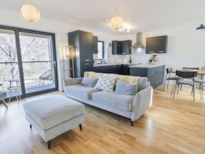 Ein modernes Wohnzimmer mit einer Couch, einem Hocker und einem Essbereich mit Stühlen.