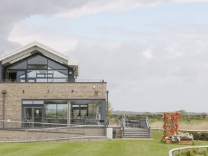 A modern building with a glass facade, a brick exterior, and a landscaped area with a decorative structure.