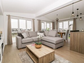 A modern living room with a sectional sofa, a wooden coffee table, and a dining area with a table and chairs.