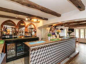 Un espace bar avec un comptoir, des étagères remplies de bouteilles et un réfrigérateur.