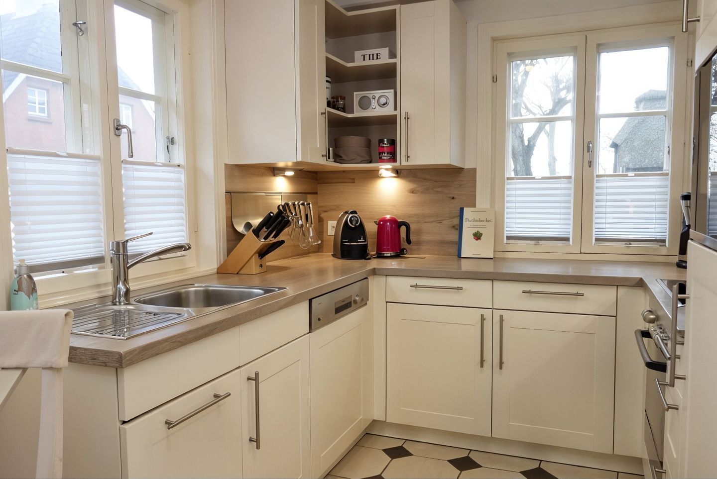 A kitchen with white cabinets, a sink, a kettle, and a knife block.