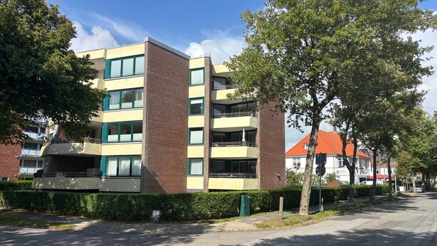 Ein mehrgeschossiges Gebäude mit flachem Dach, großen Fenstern und einer Ziegel-Fassade.
