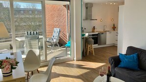 Eine moderne Wohnung mit Küche, Essbereich und einem Balkon mit Stuhl und Tisch.