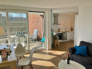 Un apartamento moderno con cocina, comedor y un balcón con una silla y mesa.