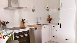 Eine moderne Küche mit weißen Schränken, einer Edelstahl-Dunstabzugshaube, einem Geschirrspüler und einer Holz Arbeitsplatte.
