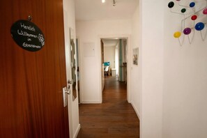 Un pasillo con una puerta de madera, un cartel de bienvenida y una decoración de pared colorida.