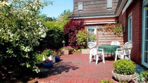 A patio with a brick floor, white chairs, and a table. - Austernfischer - Holiday apartment Austernfischer in Wyk auf Föhr - close to the beach with (Wyk auf Föhr)