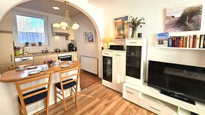 A compact kitchen with a dining area, a built-in TV, and a bookshelf. - Austernfischer - Holiday apartment Austernfischer in Wyk auf Föhr - close to the beach with (Wyk auf Föhr)