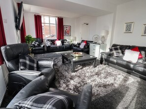 Ein Wohnzimmer mit einer Sofagarnitur, einem Couchtisch und einem Fernseher.