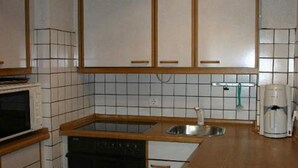 Eine kompakte Küche mit Mikrowelle, Backofen, Spüle und Kaffeemaschine.