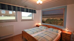 Ein Schlafzimmer mit einem hölzernen Bett, zwei Nachttischen, einem Heizkörper und einem großen Landschaftsbild an der Wand.