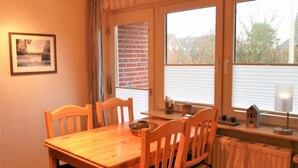 Ein Essbereich mit Holztisch und Stühlen, einem Heizkörper und einem Fenster mit Jalousien.