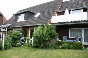 Ein zweistöckiges Haus mit Satteldach, umzäuntem Garten und sichtbarer Garage.