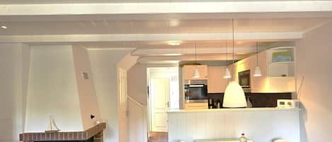 Eine moderne Küche mit Backofen, ein Essbereich mit Tisch und Stühlen sowie ein Kamin.