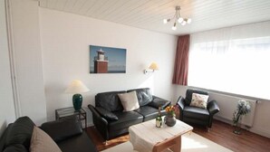 Un salon avec un canapé en cuir noir, une table basse en bois et un tableau accroché au mur.