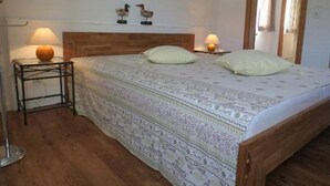Une chambre à coucher avec une tête de lit en bois, deux lampes de chevet, une couvre-lit à motifs et une table de chevet avec une lampe.