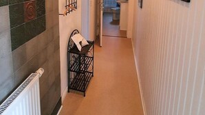 En smal gang med en radiator, knagerække og billeder i rammer på væggene.