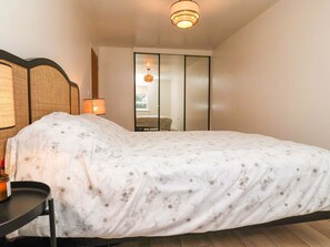 A bedroom with a bed, a bedside table, a lamp, a sliding door, and a ceiling light fixture. - Apartment, Harrogate (Harrogate)