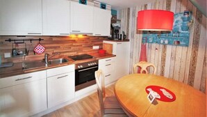 A kitchen with white cabinets, a wooden countertop, a red hanging light, and a dining table with a red coaster. - Bredland 2a - Whg. 5 - Holiday apartment in Nieblum: 52 m², terrace & only 200 m to the beach (Nieblum)