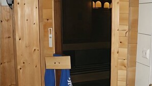 Interior de madera con una puerta, un perchero y un cesto de basura pequeño.