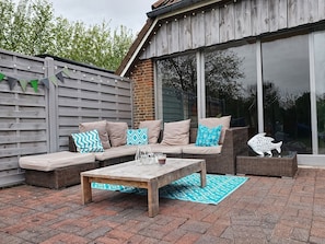 An outdoor patio with a sofa, a table, and a decorative fish sculpture. - Nis Puk - FW Hooge - Space for up to 5 people, garden & 500 m to the beach (Utersum)