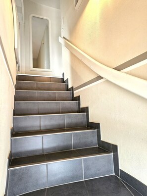 A staircase with dark tiles and white walls, leading to a door at the top. - Eltimjo 1 - Holiday apartment for 2 persons - Eltimjo 1 vacation apartment in Nieblum: (Nieblum)