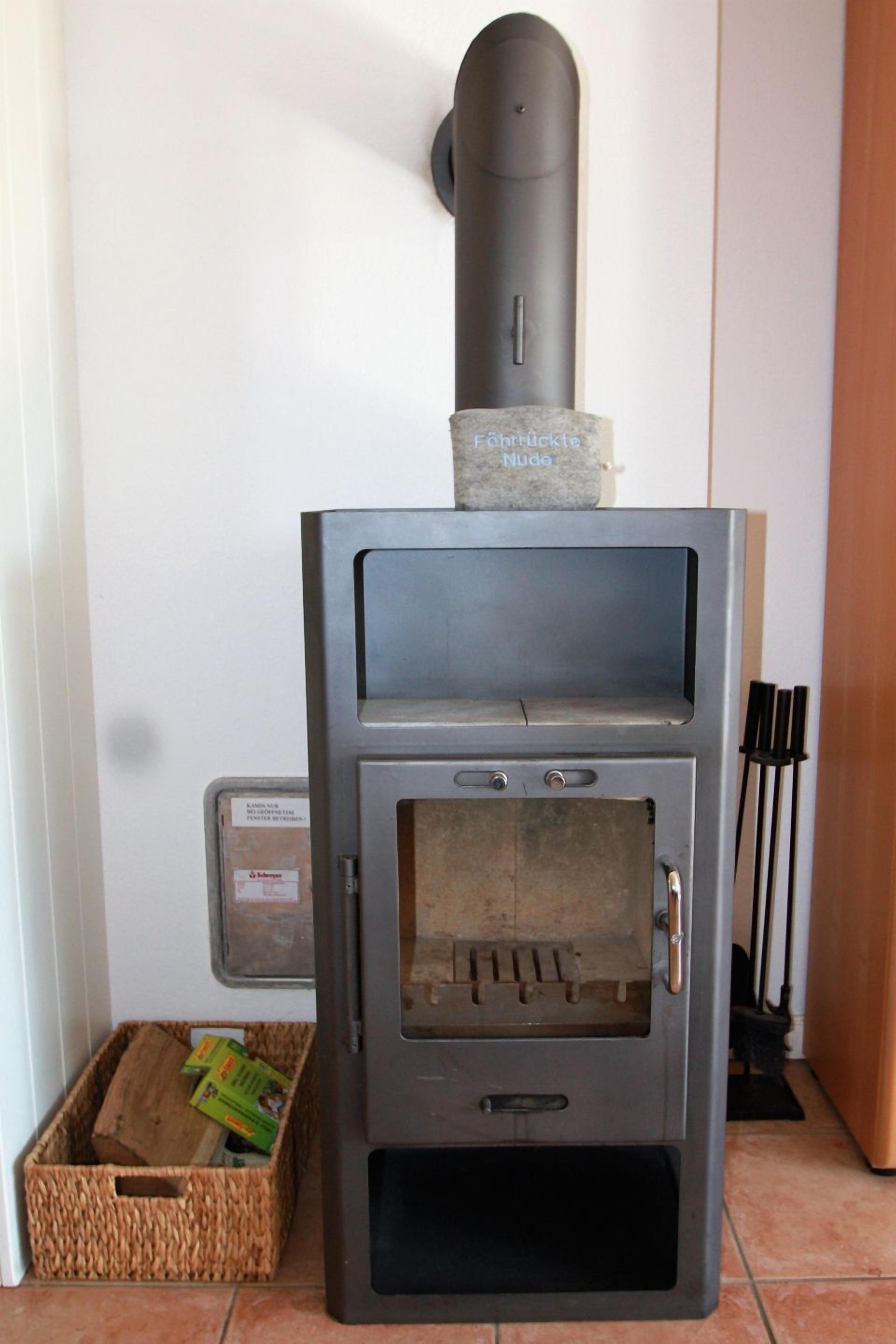 A wood stove with a chimney, a control panel, and a storage compartment.
