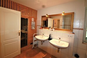 A bathroom with two sinks, a mirror, and a wooden panel wall. - Palais am Südstrand - Whg. 2 - Holiday apartment on the south beach: close to the beach and (Wyk auf Föhr)