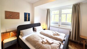 Un dormitorio con dos camas, una mesita de noche, una ventana con cortinas y decoración en la pared.