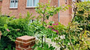Un edificio de ladrillo de dos plantas con techo a dos aguas, varias ventanas y una chimenea visible.