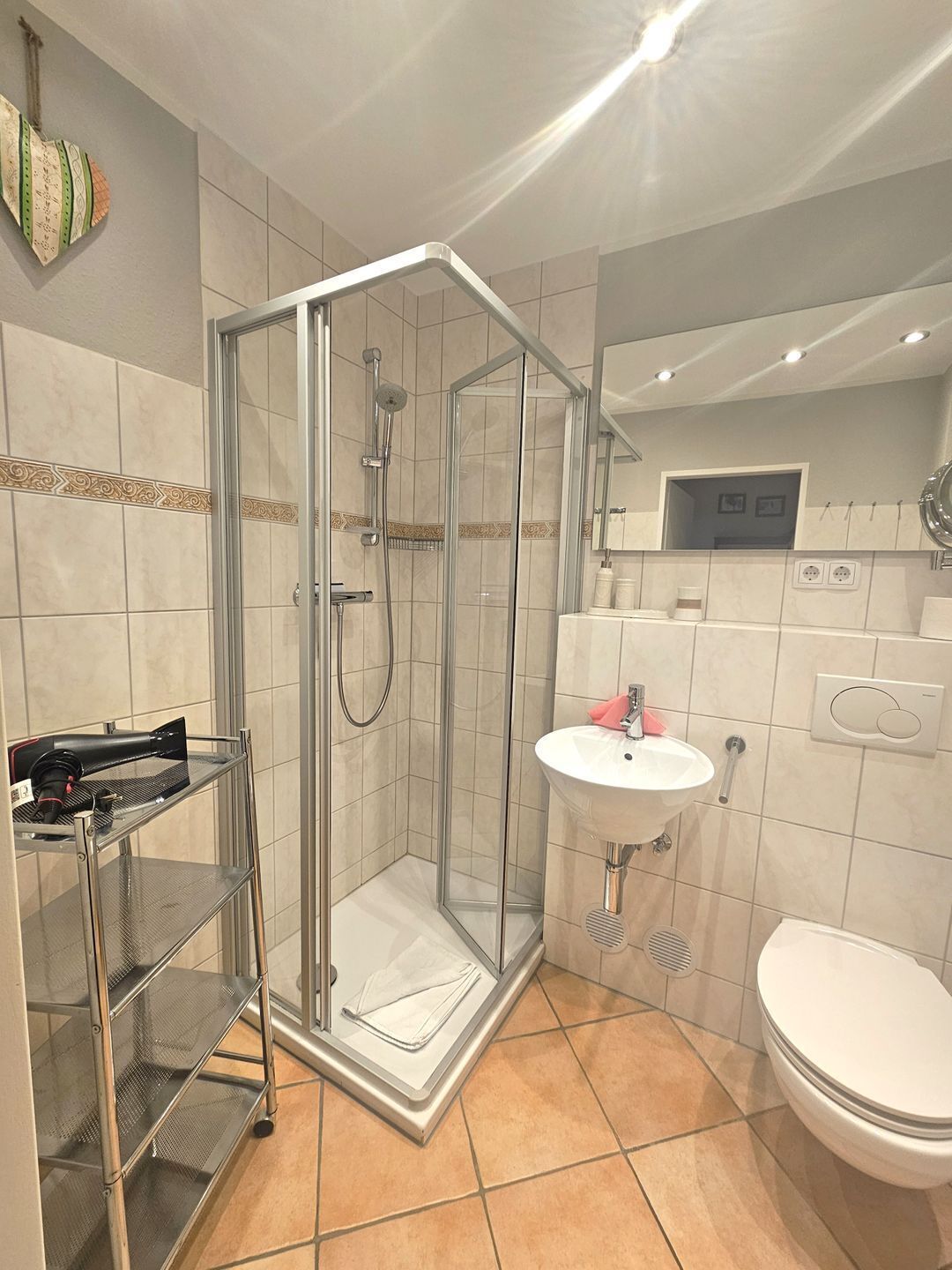 Ein modernes Badezimmer mit einer gläsernen Duschkabine, einem weißen Waschbecken und einer Toilette.