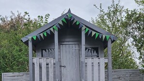 A wooden playhouse with a slide and a ladder leading up to it. - Nis Puk _FW Habel (ground floor) - vacation apartment in Utersum: 50 m² with terrace, close to the beach (Utersum)