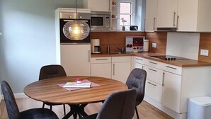 Eine moderne Küche mit weißen Schränken, einem Holztisch und schwarzen Stühlen.