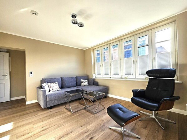 A living room with a sofa, coffee table, ottoman, and a chair. - Haus am Walde - Ground floor - Bright vacation apartment in Haus am Walde on the ground floor, 380 m to the (Wyk auf Föhr)