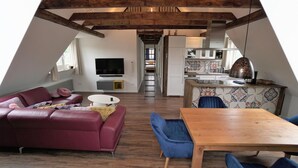A loft-style living space with a sofa, dining table, and kitchen area. - Seestern - Holiday apartment Seestern in Wyk on Föhr - 80 m², terrace & garden (Wyk auf Föhr)