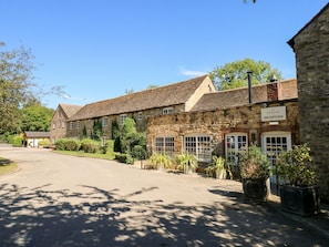 A stone building with a reception area, a paved driveway, and surrounding greenery.