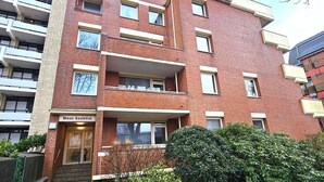 A multi-story residential building with a brick facade, multiple balconies, and a small front garden. - Mühlenblick - Apartment Mühlenblick: 60 m² near the beach in Wyk auf Föhr (Wyk auf Föhr)