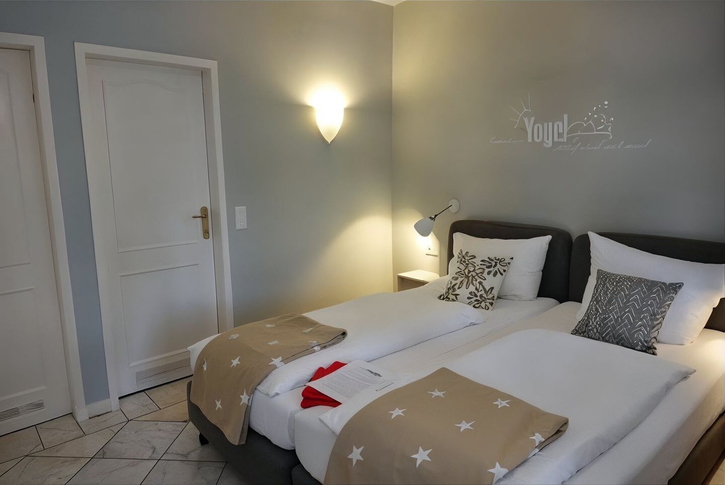 Ein Hotelzimmer mit Bett, Nachttischen, einer Wandleuchte und einer Tür.