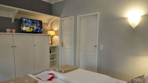 Een slaapkamer met een bed, een televisie, een kledingkast en een bedlamp.