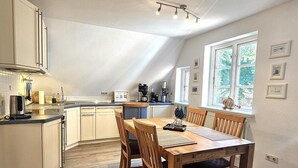 Eine moderne Küche mit Essbereich, Holzboden und einem Fenster mit Aussicht.