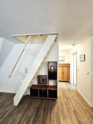 Un dormitorio tipo loft con escalera de madera, estanterías empotradas y suelo de madera.