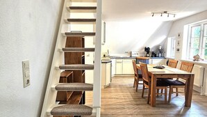 Eine Treppe führt zu einem Essbereich mit Holzboden, im Hintergrund ist eine Küche zu sehen.