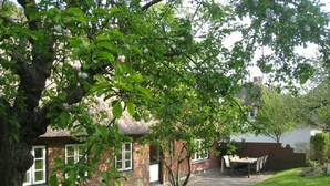 A brick house with a thatched roof, a lawn, and a table and chairs outside. - Ilskes Hus - Detached thatched house with garden, terrace & e-charging station (Oevenum)