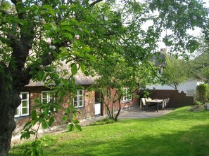 A brick house with a thatched roof, a lawn, and a table and chairs outside. - Ilskes Hus - Detached thatched house with garden, terrace & e-charging station (Oevenum)