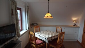 Un comedor con una mesa, sillas, un televisor, una lámpara y un tapete estampado.