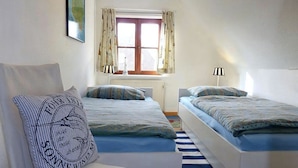 Un dormitorio con dos camas, una ventana con cortinas, un radiador y una lámpara.