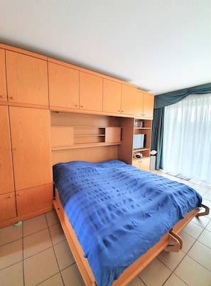 A bedroom with a bed, wooden wardrobe, and a window with curtains. - Wattwurm, Whg. 8 - Apartment Wattwurm, Whg. 8: 2strand and close to the center, (Wyk auf Föhr)