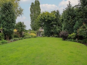 A well-maintained lawn with a gazebo in the center, surrounded by dense foliage and trees.