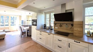 Une cuisine moderne avec des meubles blancs, une grande fenêtre et un téléviseur à écran plat.