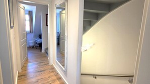 Un intérieur moderne avec un plancher en bois, un escalier et un couloir menant à une autre pièce.